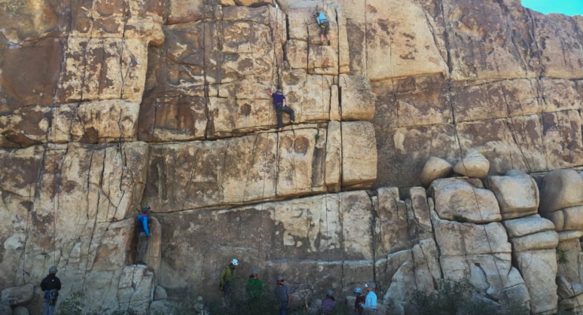a group of rock climbers make their way up a rock wall on an outward bound course